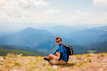 Naklejka na ściany i meble Trip to Carpathian mountains. Happy man hiker with backpack resting on top of Hoverla. Traveling in summer Ukraine