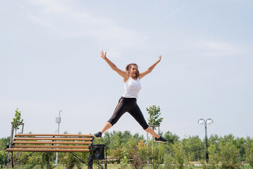 Fototapeta na wymiar Happy woman working out on the sports ground in sunny summer day jumping