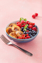 mini pancake breakfast bowl with berries and maple syrup