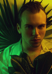 Close-up fashion portrait of caucasian handsome unshaven man underwater in sexy wet white shirt looking at camera strong face, plants background