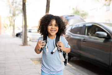 Afro handsome boy, with backpack, gets out of the car to go to school, back to school, preschool
