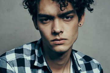 guy in plaid shirt curly hair serious facial expression close up