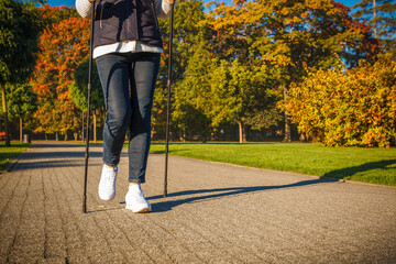 Nordic walking - middle-age woman training in city park
