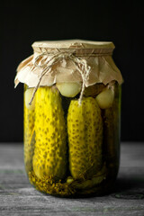 Pickled cucumbers in a glass jar on an old wooden table. Summer harvest.