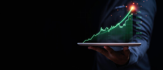 Businessman holding tablet with increasing virtual investment graph and chart for stock market...