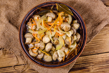 Canned mushrooms with carrot and onion in a ceramic bowl. Top view