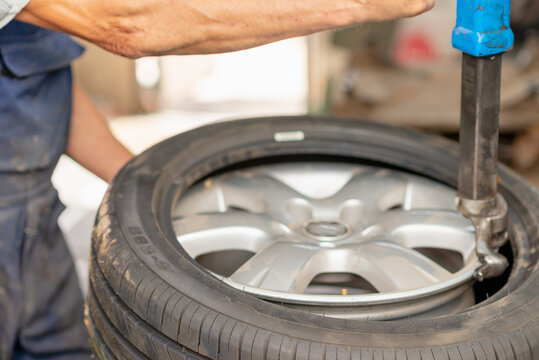 Mechanic changing tire in car service. Tire rotation machine.Car mechanic mounts tire on wheel in a workshop.