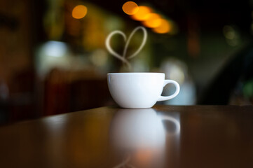 White Hot coffee cup of love on Wood Table in blurred Coffee Shop background.Photo with soft focus.