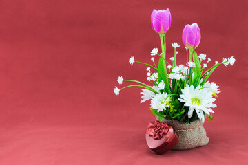 Flower bouquet in a sack and read heart gift box, Isolated on gray pink.