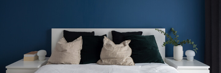 Navy blue wall in bedroom with double bed, panorama
