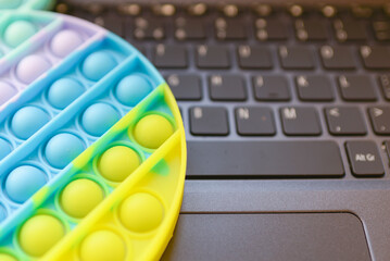 Multicolored antistress silicone Pop it.Toy on a keyboard laptop.Businessman or freelancer relaxes. closeup.relax popit