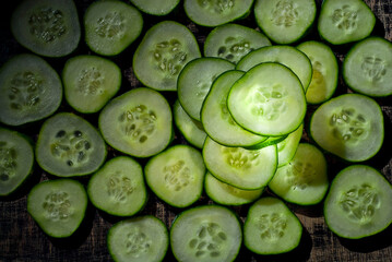Pieces of cucumber on a pile close up. Cucumber slices on a black background. Contrasting dramatic light as an artistic effect.