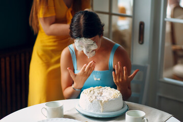 Young woman dips face in white cake with cream. Happy birthday concept