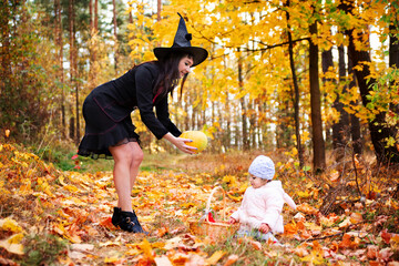 black witch with little toddler bunny in the autumn forest. halloween celebration, costume party