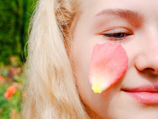 The use of rose oil and rose water, rose petals on the eyelids of a young and beautiful girl. Rose essential oil. Selective focus