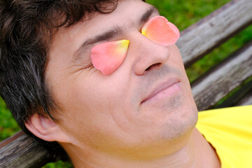 The use of rose oil and rose water, rose petals on the eyelids of a man. Rose essential oil. Selective focus.