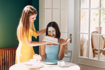 Young woman dips face in white cake with cream. Happy birthday concept