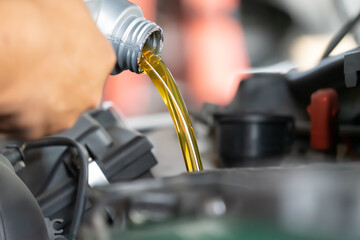 Pouring engine oil to car engine. Fresh oil poured during an oil change to a car.