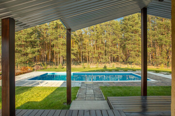 Backyard of a modern country house with a swimming pool. House in forest. Space for text. High quality photo