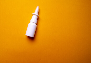 Bottle of nose drops on a yellow background close-up. Spray for the nose. View from above