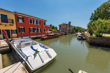 Port of Torcello island with many speed boats and two traditional water taxis made of wood moored. Venetian lagoon, Venice, UNESCO world heritage site, Veneto, Italy, Europe.