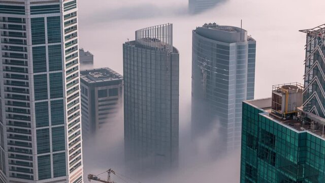 Rare early morning winter fog above the Dubai Marina skyline and skyscrapers rooftops aerial timelapse.