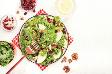Kale salad with dried cranberry, green apples and walnuts. Healthy food, top view, white kitchen table, negative space