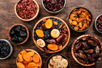 Dried fruits bowl. Healthy food snack: sun dried organic mix of apricots, figs, raisins, dates and other on wooden table, top view