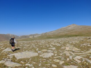 Fototapeta premium jeune femme qui randonne en montagne avec sac à dos dans les Pyrénées hors sentier dans l'herbe et les crêtes