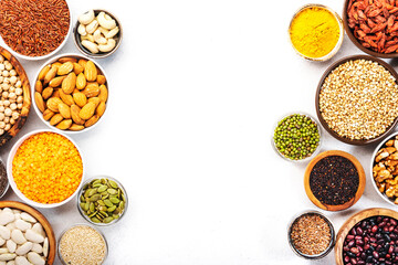 Set of superfoods, legumes, cereals, nuts, seeds in bowls on white table. Copy space, top view