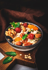 Muesli bowl and organic ingredients for healthy breakfast. Granola, nuts, dried fruits, oatmeal, whole grain flakes on white table