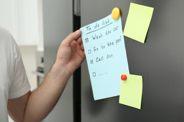 Man taking to do list from refrigerator door in kitchen, closeup