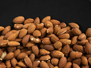 almond in black plate on wood table for food and health  concept