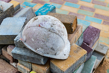 An old work helmet rests on folded paving slabs. Rest break at the construction site. Hard work of...