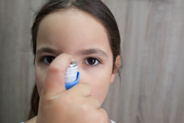 Child girl using medical spray for breath. Inhaler