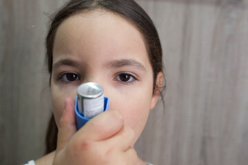 Child girl using medical spray for breath. Inhaler
