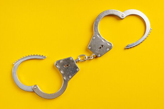 Opened handcuffs on yellow background.