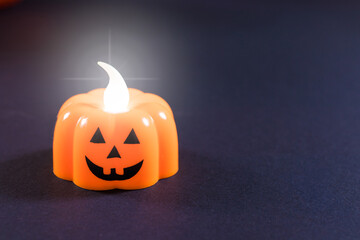 Halloween banner place for text - a candle in the form of a pumpkin glows against a dark background. Congratulations on the holiday.