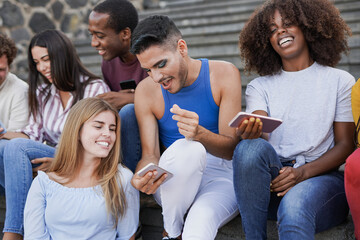 Group of young diverse friends using mobile phone in the city - Multiracial people having social moment and enjoy technology
