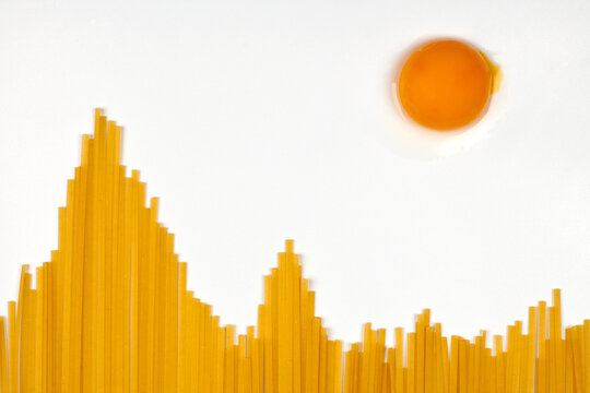 Uncooked spaghetti in shape of hills and egg as sun. Travel snack concept