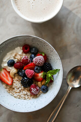 Oatmeal with berries and nuts in a light plate on a table with a tablecloth. Healthy breakfast. Table setting for breakfast.
