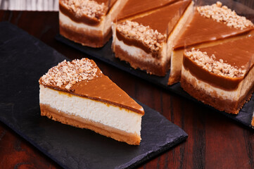 Pieces of cheesecake with chocolate icing on black stone boards. Traditional popular dessert. Space for text. High quality photo