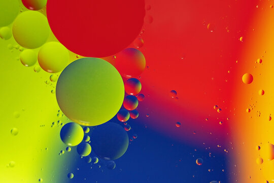 Macro photography of the drops on the water surface.Multicolored vibrant background.Cosmic circles looks like molecule structure.Backdrop with copy space,good as template.