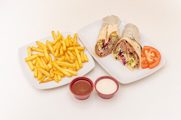 Durum menu cut in half and rolled with aluminum foil garnished with potatoes and sauces and with a lot of meat of lamb kebab with lettuce and red cabbage