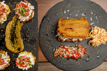 Top view image of Venezuelan patacones and arepas with coleslaw, pico de gallo, fresh cheese, parsley and guacamole