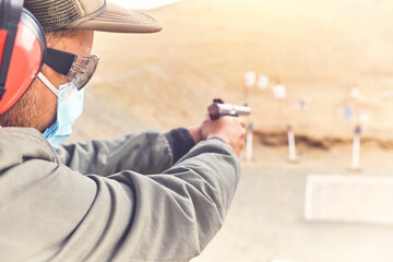 Man with hand gun aiming at shooting range and releasing stress. Selective Focus