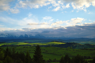 Piękne, zielone łąki podświetlone promieniami słonecznymi z widokiem na Tatry.