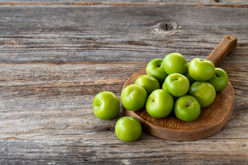fresh green plums on wood background. Copy space