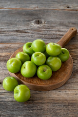 fresh green plums on wood background