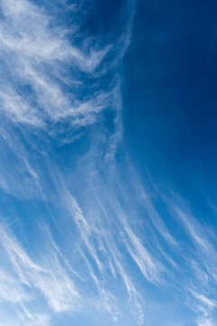 Verticle white cirrus clouds moving to cover blue sky